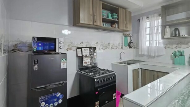 A kitchen with a refrigerator, stove, microwave, wooden cabinets, and a sink. - Charming 2-bedroom apartment in enjoyable Naivasha getaway (Naivasha)