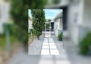 A pathway leading to a building with a covered entrance, surrounded by greenery and a gravel surface. - View Private Suite near LEGOLAND & Hospital (Winter Haven)