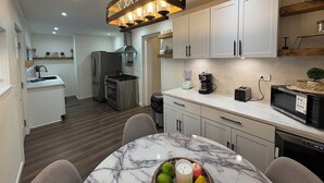 Una cocina moderna con armarios blancos, encimera de mármol y una isla central con frutero.
