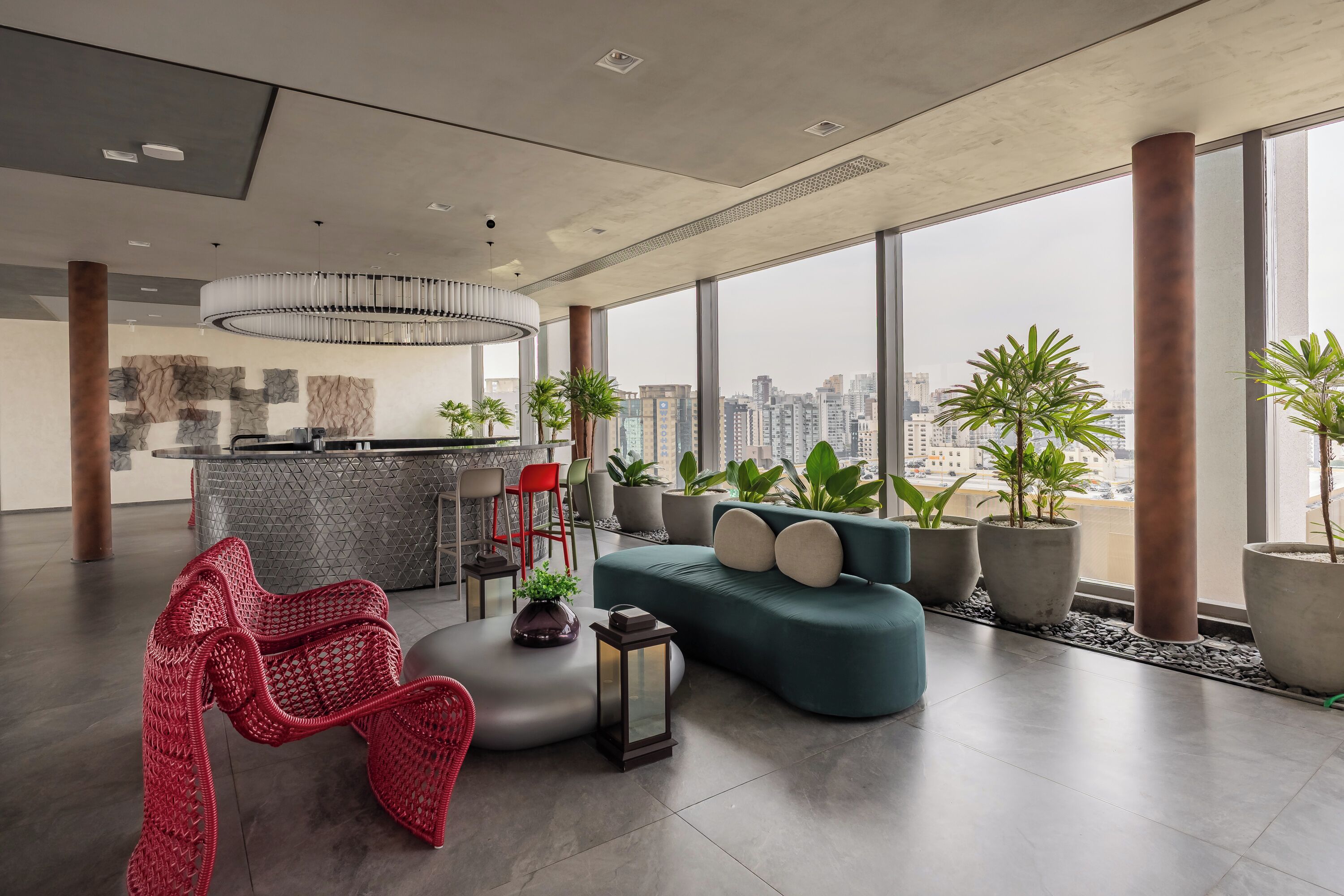 Un intérieur moderne avec une grande fenêtre, un canapé, un fauteuil rouge et un coin bar.