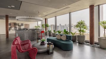 A modern interior with a large window, a sofa, a red chair, and a bar area.