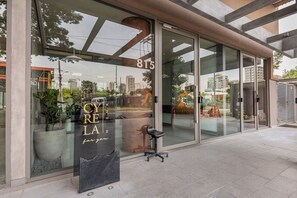 A modern building with large glass windows, a visible address number 815, and a seating area outside. - StayHome - Moema Cyrela - Piscina & Gym (São Paulo)
