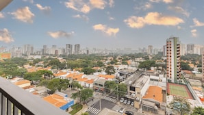 Un paisaje urbano con edificios residenciales y comerciales, un rascacielos destacado y un cielo despejado con algunas nubes.