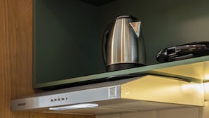 Una cocina con una campana de acero inoxidable, un hervidor y dos ollas sobre una placa de inducción.