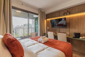 A hotel room with a large bed, a TV mounted on the wall, a balcony with a view of buildings, and a coffee machine on a side table. - StayHome - Moema Cyrela - Piscina & Gym (São Paulo)