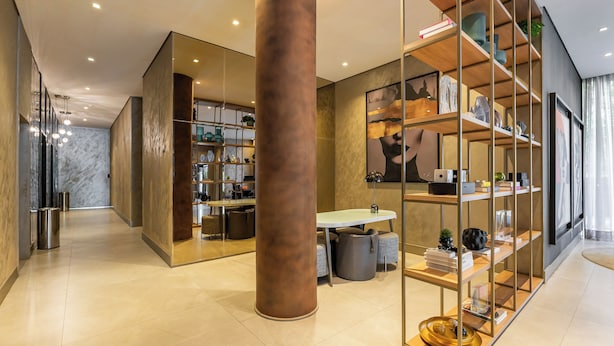 Un interior moderno con una columna central, un comedor y una estantería.