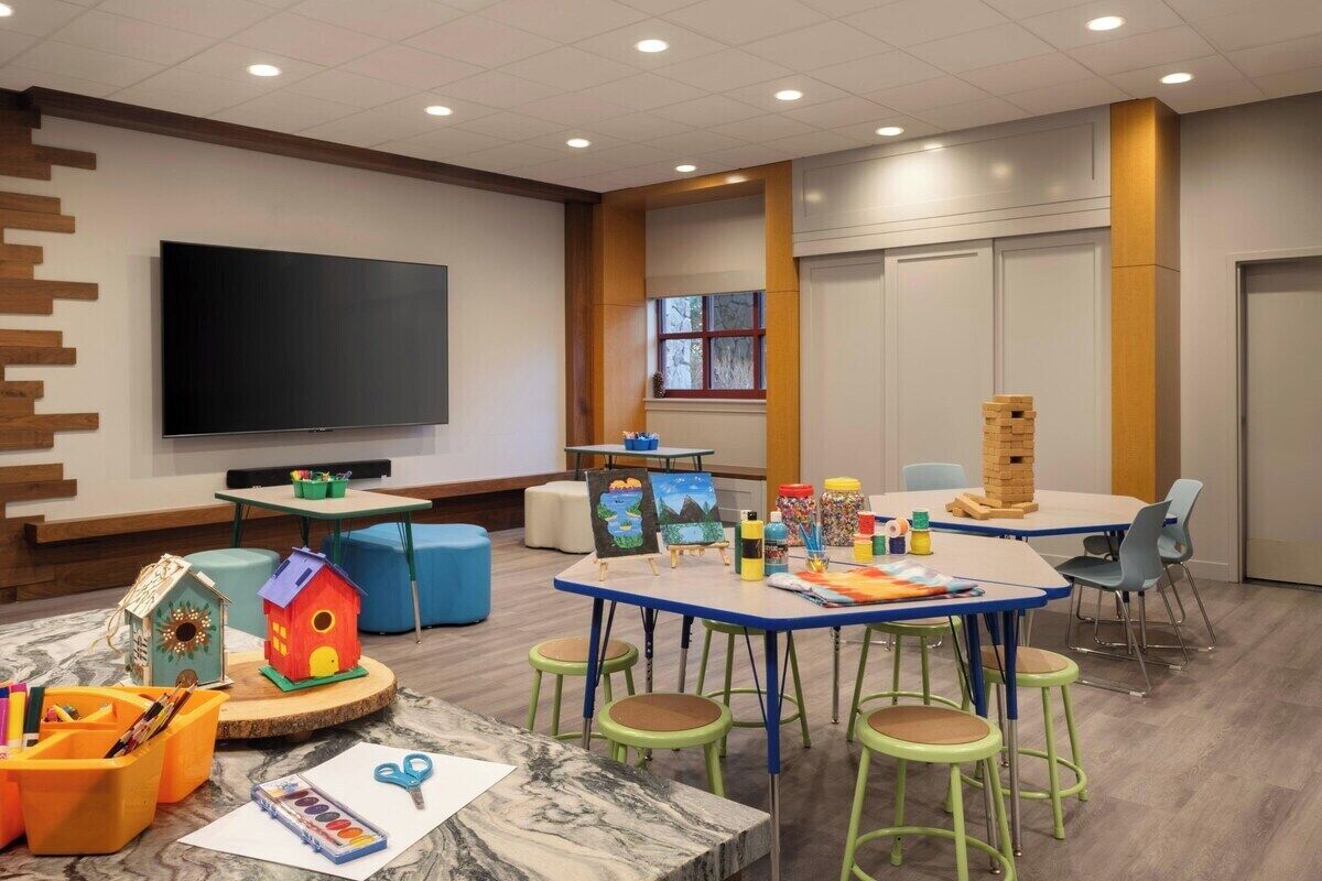 Un espace de jeux pour enfants avec des tables, des chaises et des jouets.