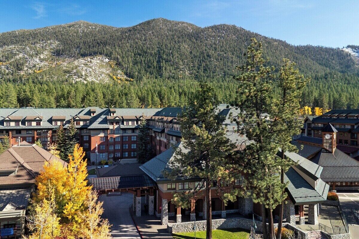 Un hotel con varias edificaciones, un patio central y montañas al fondo.