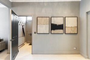 A hallway with a door, a radiator, and three framed artworks on the wall. - Elegant Four-Bed Fulham Home (London)