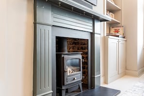 A modern fireplace with a stone wall behind it, a white cabinet to the right, and a book titled 'Ray Conniff's World of Hits' on top of the cabinet. - Elegant Four-Bed Fulham Home (London)