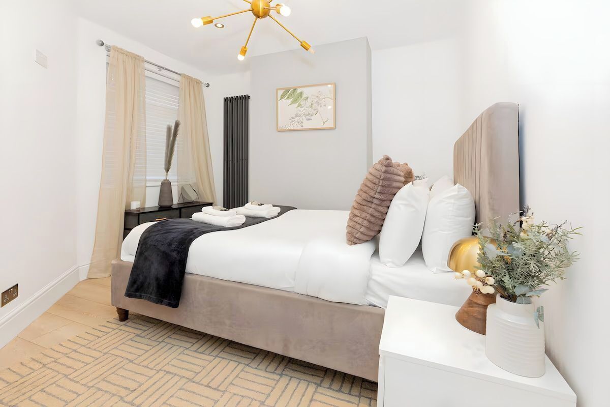 A neatly arranged bedroom with a bed, bedside table, and a decorative vase.