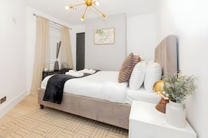 Een keurig opgemaakt slaapkamer met een bed, nachtkastje en een decoratieve vaas.