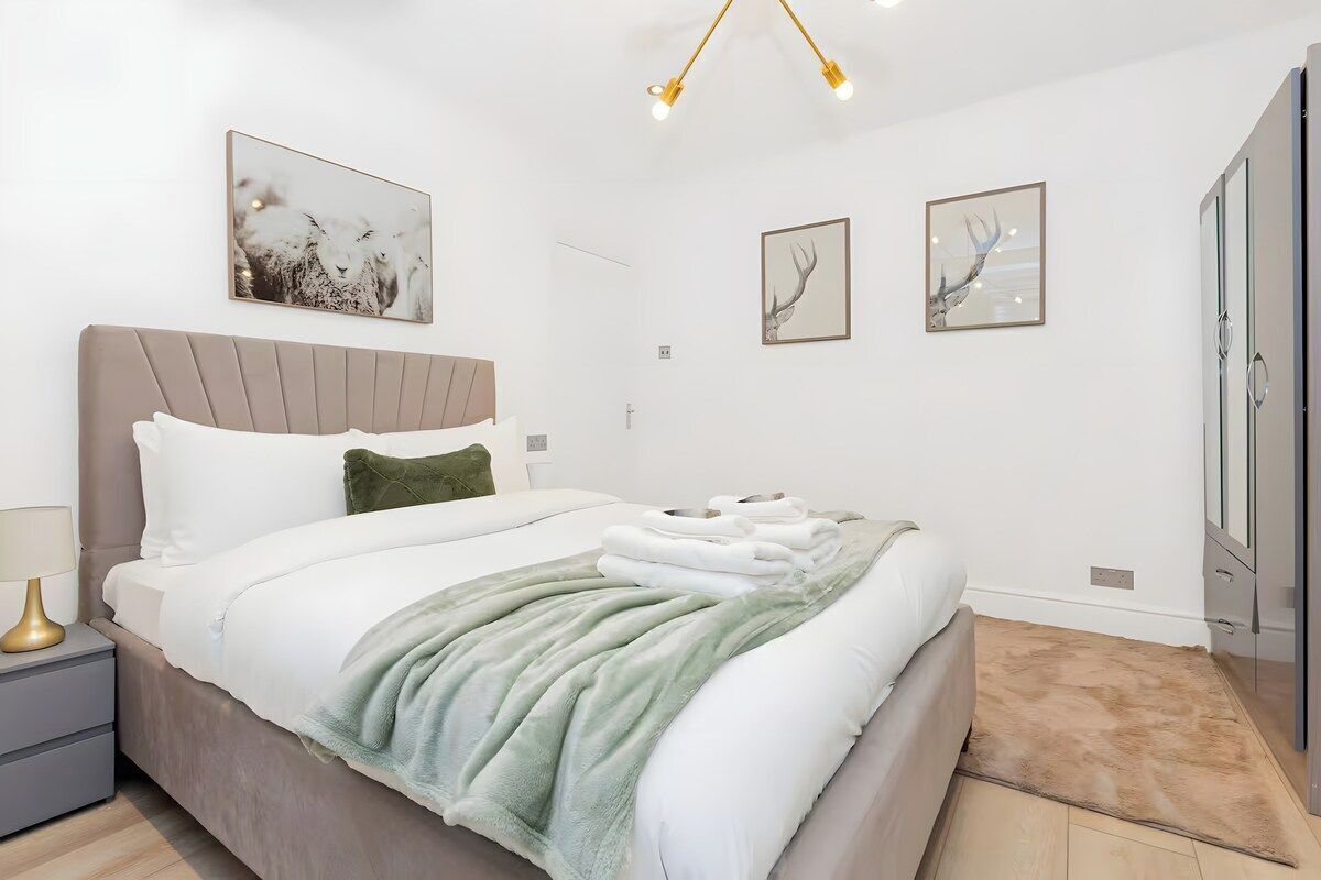 Een moderne slaapkamer met een groot bed, een nachtkastje, een lamp en kunst aan de muren.