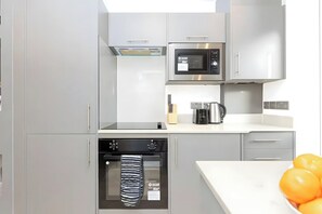 A modern kitchen with a microwave, oven, and coffee maker. - Modern London Apartment for Business Stays (Greater London)