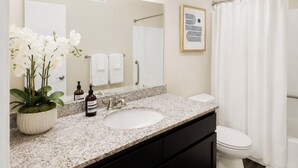 Baño con lavamanos, espejo y cortina de ducha.