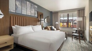 Habitación de hotel con una cama grande, un escritorio, una silla, un televisor y una ventana con vistas a edificios.