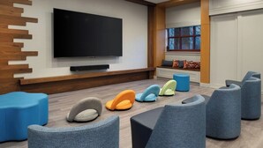 Un área de estar moderna con un televisor de pantalla plana, asientos cómodos y un ventanal con vistas.