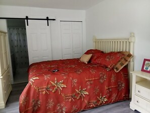 Ein Schlafzimmer mit Bett, Schrank, Heizkörper und Tür.