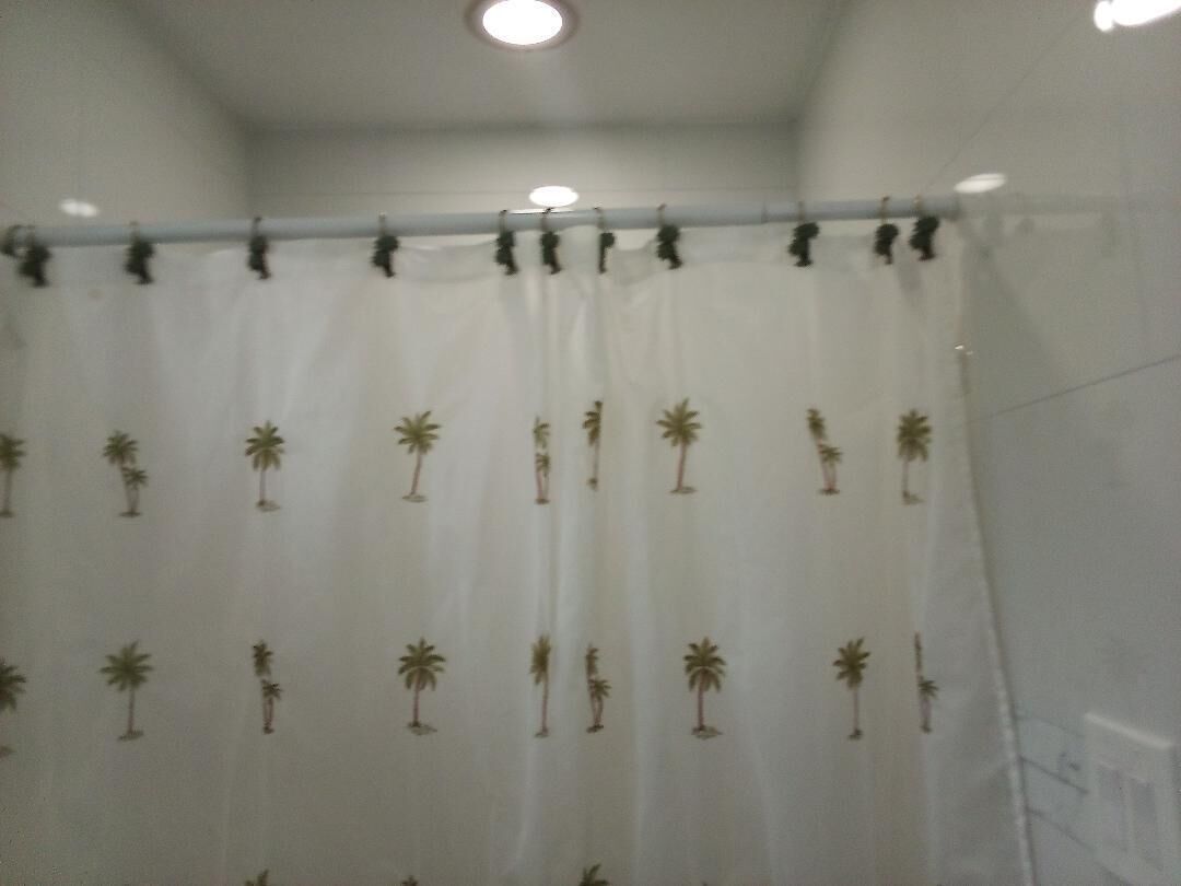 Ein Badezimmer mit Duschvorhang, verziert mit Palmenmotiven.