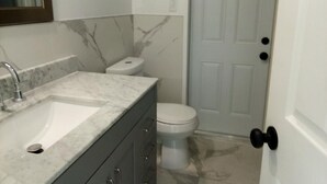 A bathroom with a marble sink, a toilet, and a door with a round doorknob. - Spacious 3-bedroom house in Fort Myers with pool, straight drive to the beach (Fort Myers)