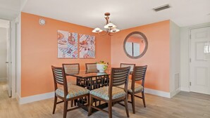 A dining area with a round table, four chairs, and a chandelier. - Tangerine Tides: Resort Pool/Spa, On Beach, Lanai (Fort Myers Beach)