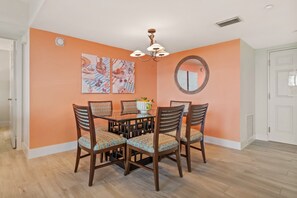 A dining area with a round table, four chairs, and a chandelier. - Tangerine Tides: Resort Pool/Spa, On Beach, Lanai (Fort Myers Beach)