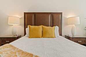 Una habitación de hotel con una cama grande, dos mesitas de noche y un cabecero.