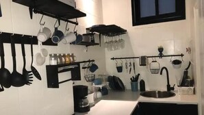 Una cocina con utensilios colgantes, una cafetera y un lavabo.