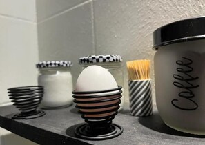 Eine Küchenarbeitsplatte mit einer Kaffeemaschine, einem Kaffeeglas und einem Stapel Essstäbchen.