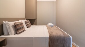 A small, single-bed room with a plain white bedspread, two pillows, a folded towel, and a blanket on the bed. - 9 min From Copacabana Beach Ml905 (Rio de Janeiro)
