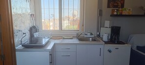 Een kleine keuken met een spoelbak, koffiezetapparaat en een koelkast.