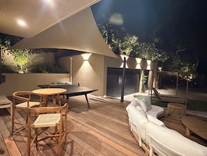 Un patio al aire libre con mesa y sillas de madera, un sofá y una parrilla.