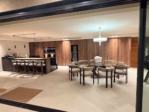 Une cuisine moderne dotée d’un îlot central, de tabourets de bar et d’un coin repas avec des tables et des chaises rondes.