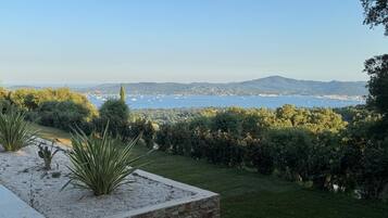 Un giardino curato con vista su una cittadina costiera e montagne sullo sfondo.