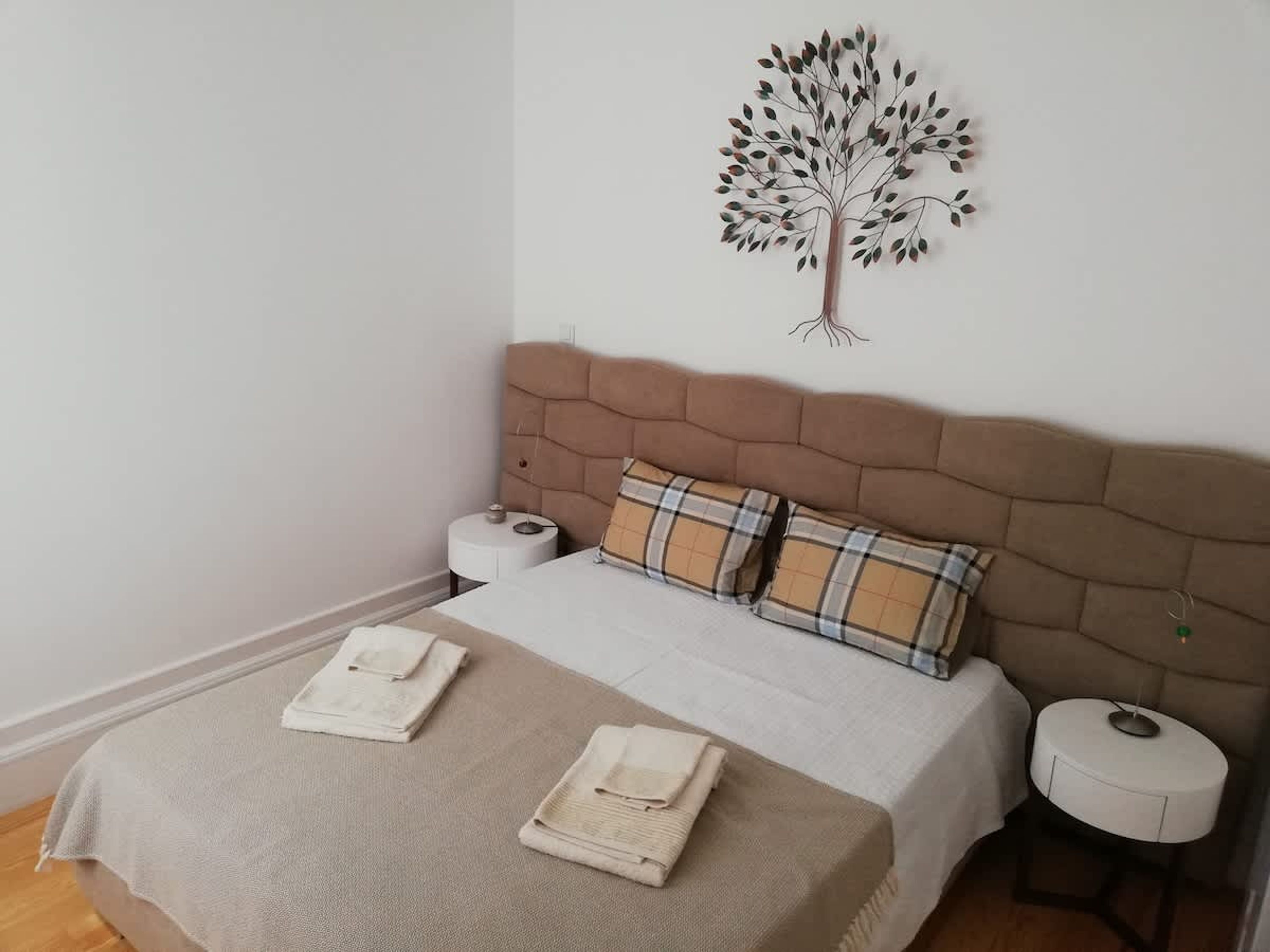Ein Schlafzimmer mit einem Kopfteil, zwei Kissen, einem Bett, einem Nachttisch und einer Wanddekoration.