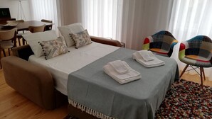 A hotel room with a bed, a desk, two chairs, and a colorful rug. - Downtown Apartment Porto by Liiiving (Porto)