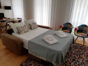A hotel room with a bed, a desk, two chairs, and a colorful rug. - Downtown Apartment Porto by Liiiving (Porto)