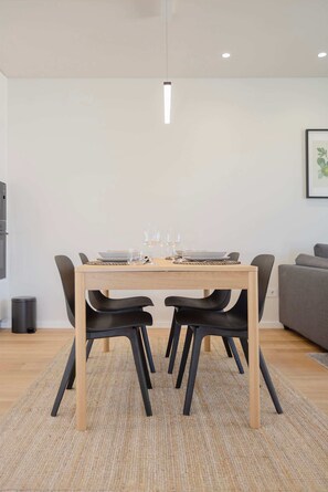 Ein Essbereich mit einem Holztisch, schwarzen Stühlen und einem grauen Sofa.