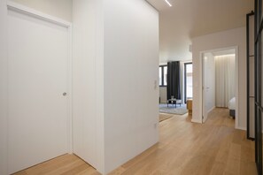 Un pasillo con piso de madera, paredes blancas y puertas que dan a otras habitaciones.