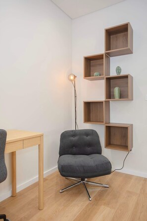 Ein modernes Zimmer mit einer Holzeinrichtungsregal, einem grau gepolsterten Sessel und einem Holztisch.