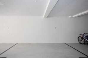 Eine geräumige, leere Tiefgarage mit Betonböden und -wänden, gekennzeichneten Parkplätzen und einem Fahrrad in einem der Stellplätze.
