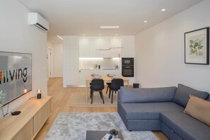 Ein modernes Wohnzimmer mit einem grauen Sofa, einem Flachbildfernseher und einem Couchtisch.