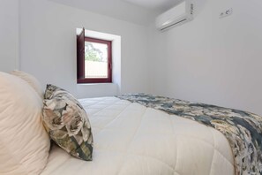 A bedroom with a bed, a window, and an air conditioning unit.