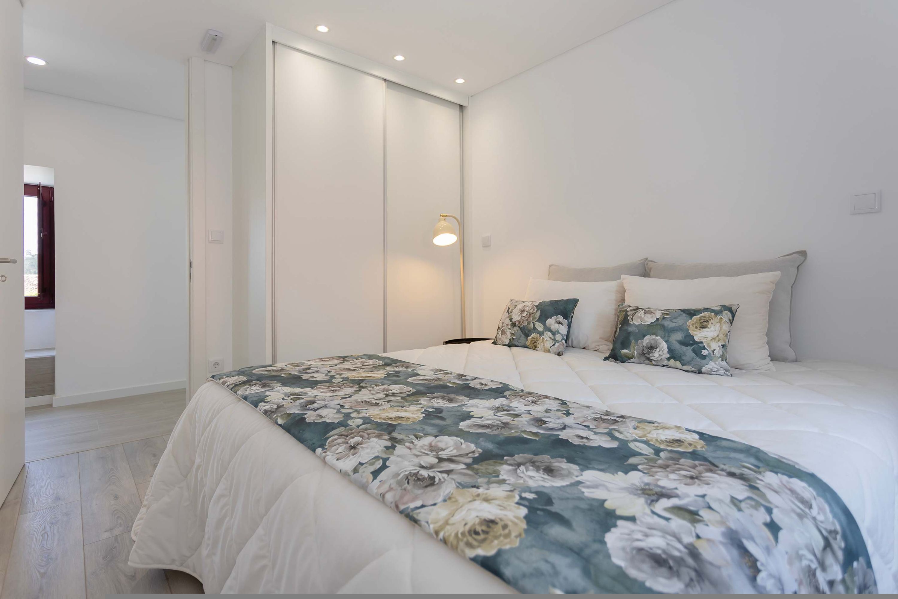 Ein Schlafzimmer mit einem Bett, einem Nachttisch, einem Spiegel und einer Tür.