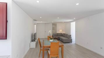 A modern living room with a dining area, a grey sofa, and a TV.