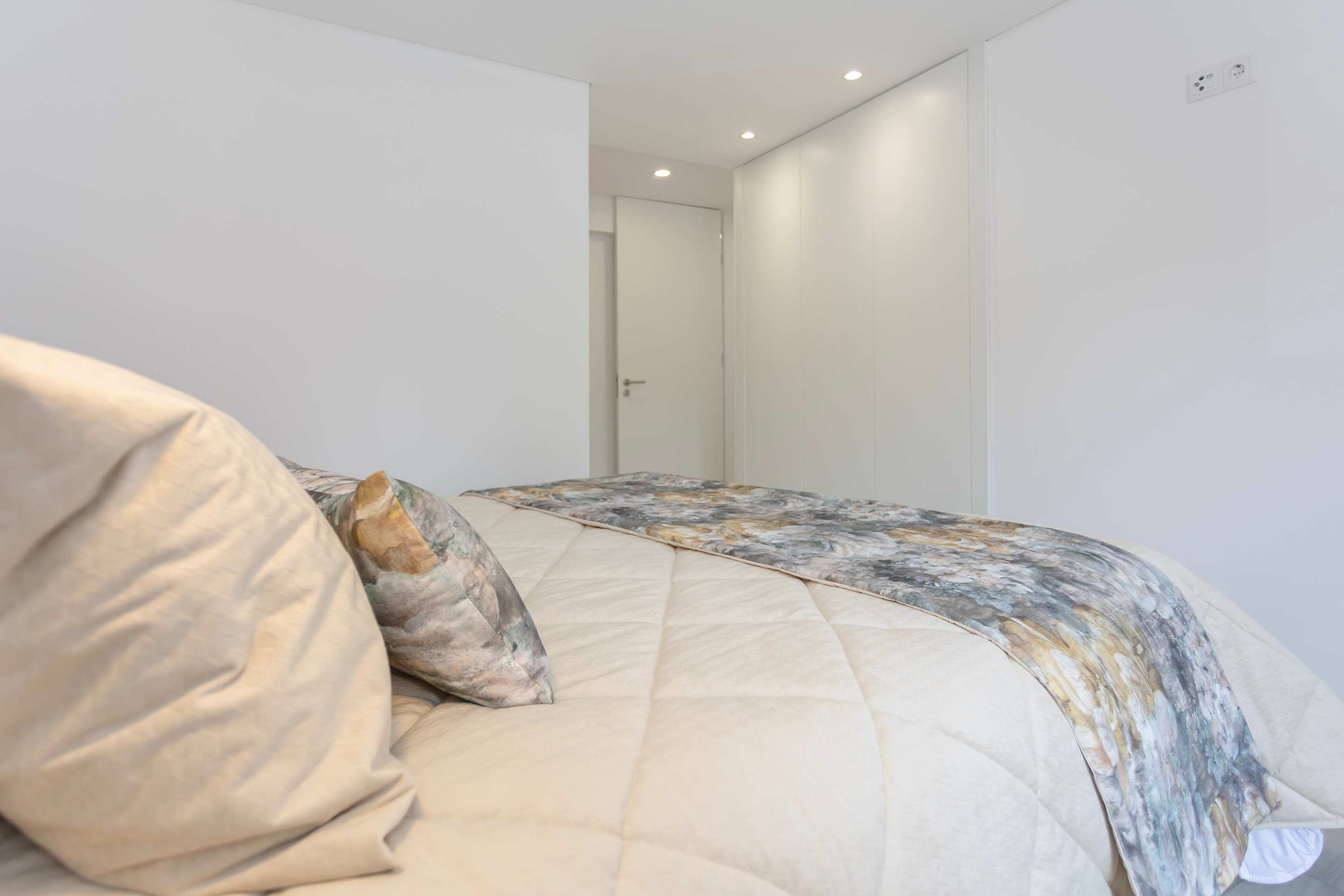 Ein Schlafzimmer mit Bett, Kissen, einer Tür und einer Steckdose.