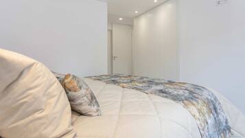 Ein Schlafzimmer mit Bett, Kissen, einer Tür und einer Steckdose.
