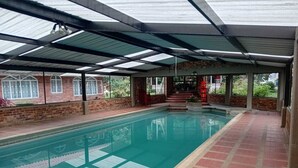 An indoor swimming pool with a tiled floor, a covered roof, and brick walls.
