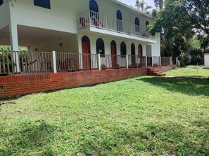 A two-story building with a covered porch and a fenced yard.