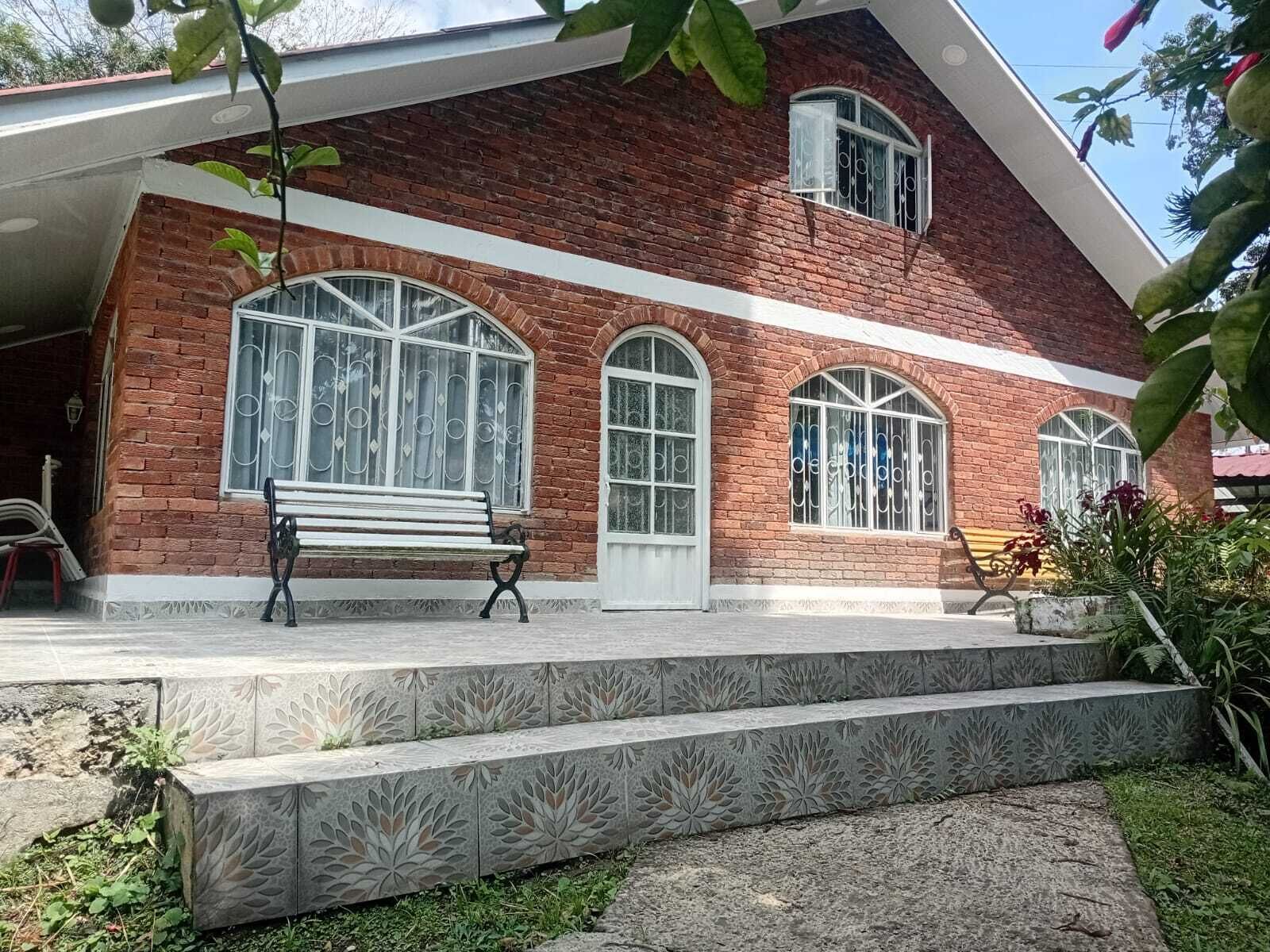 A brick building with large arched windows and a bench outside.